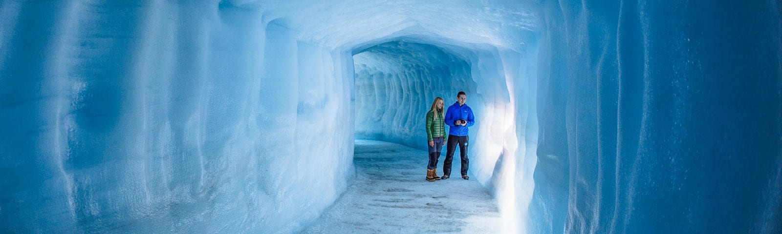 Couple exploring man made ice cave in Iceland