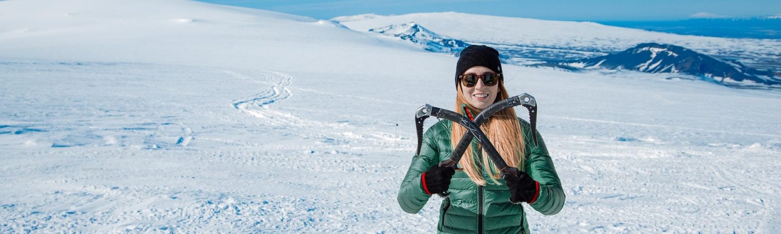 Girl holding ice axes on glacier in Iceland