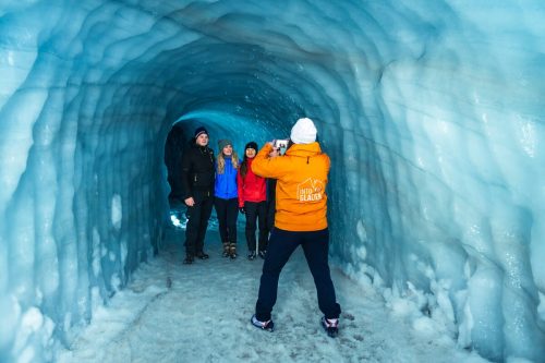 Group taking photos against blue ice walls inside ice tunnel at Langjokull glacier in Iceland