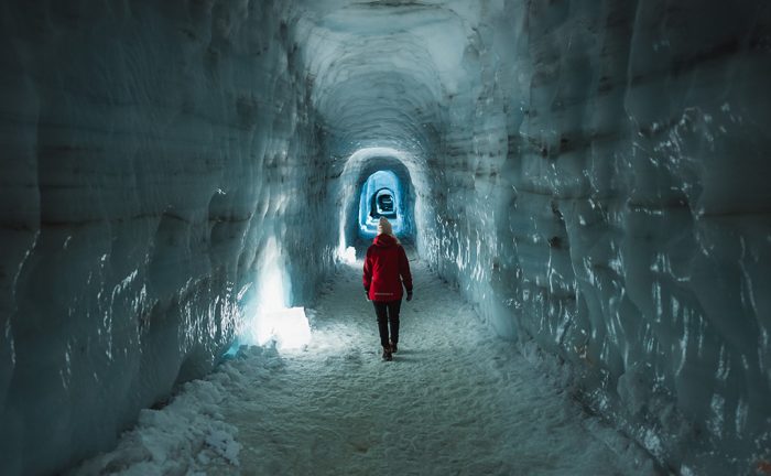 a woman in a red coat in an ice tunnel